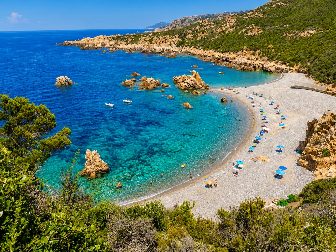 Cala Tinnari, Trinità d'Agultu — mezzaluna selvaggia di ciottoli chiari tra rocce granitiche e mare blu intenso